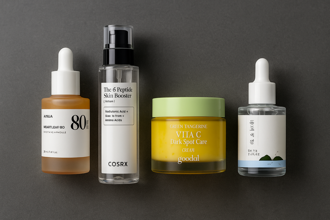 Flat lay of four Korean skincare products for men on a dark grey background — including Anua Heartleaf Ampoule, COSRX 6 Peptide Booster, Goodal Vita-C Cream, and Round Lab Dokdo Ampoule. Clean, minimalist layout ideal for a male skincare routine blog.